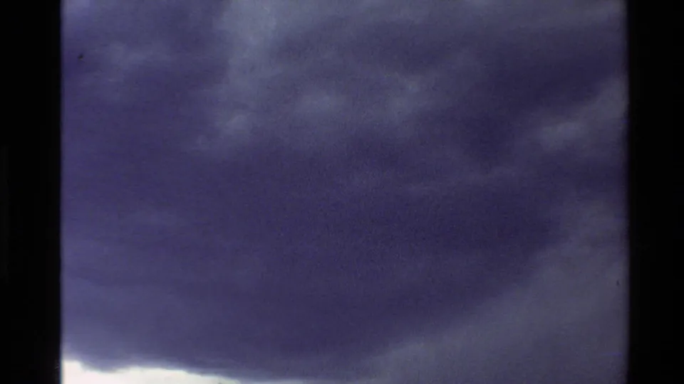 8mm home-movie view of a dense storm cloud moving across a mountain horizon in the Western U.S.