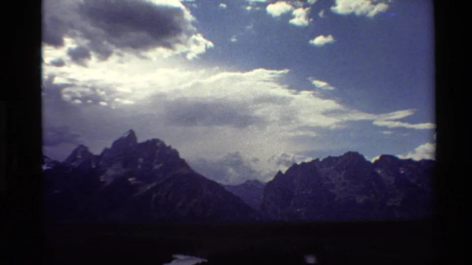 1980 8mm Western USA mountain view holding on rugged peaks beneath layered cloud cover.