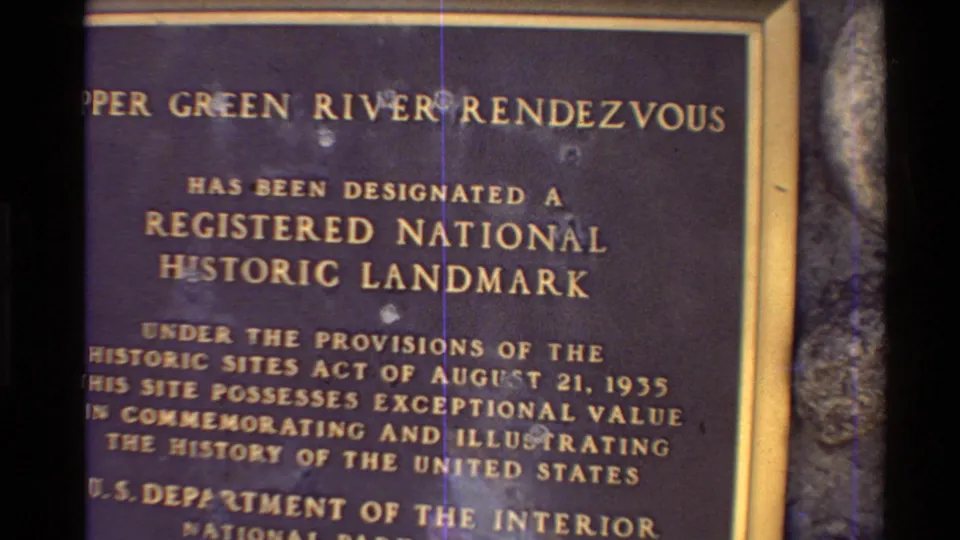 Close 8mm frame of a plaque stating the Upper Green River Rendezvous designation as a Registered National Historic Landmark.