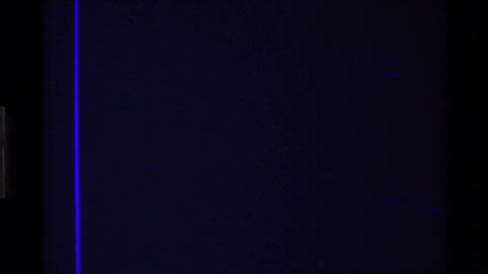 Mostly underexposed 8mm frame from the aerial sequence, with faint blue image detail, dark film area, and a vertical purple film line.
