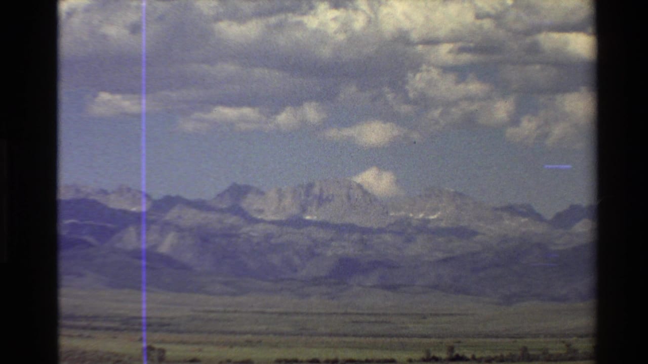 1980 Western USA home-movie view of a broad plain leading to distant mountains beneath a cloud-filled blue sky.