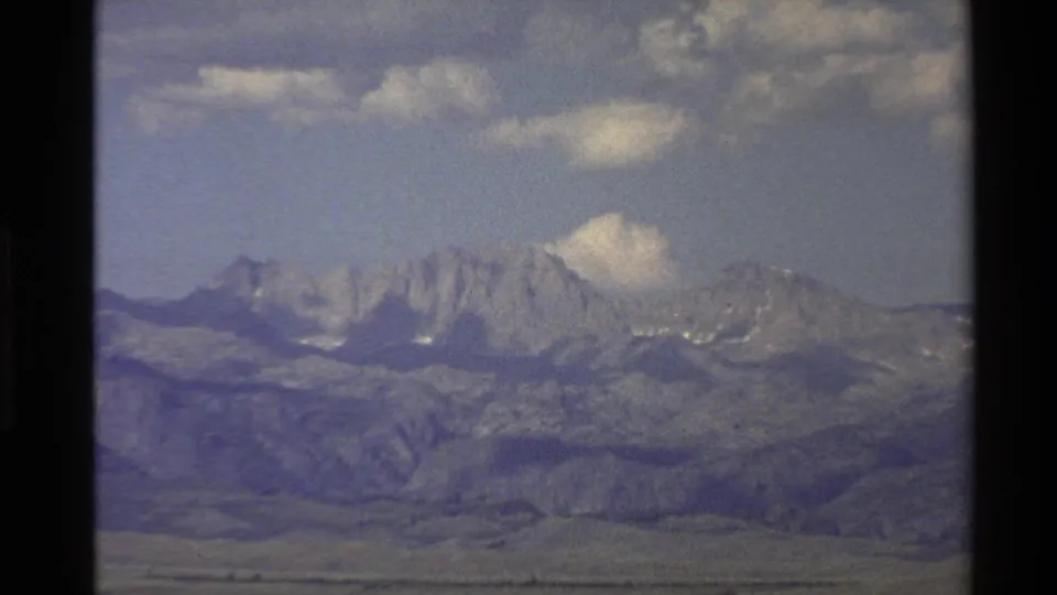 Closer 1980 home-movie view of snow-dusted Western U.S. mountain peaks, foothills, and open valley terrain.