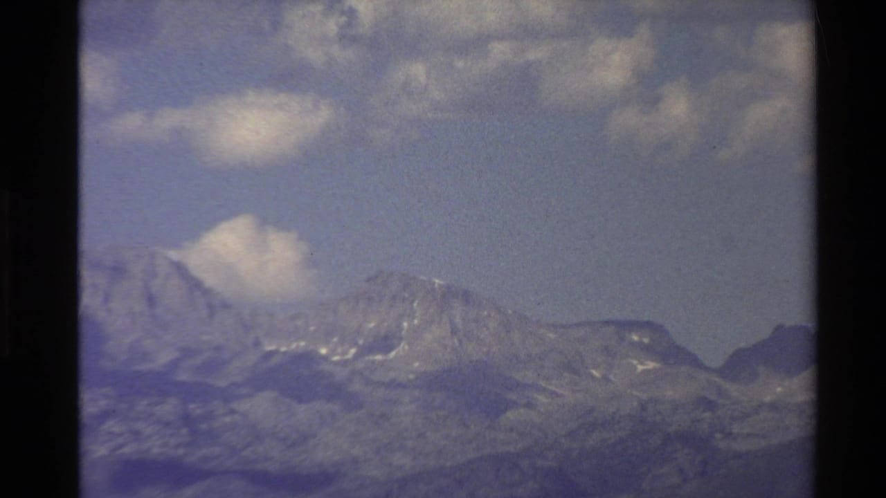 Mountain peaks and ridges seen beneath drifting clouds.