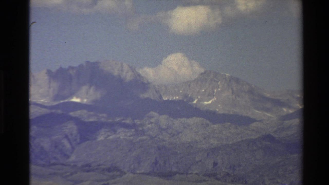 Mountain ridge and clouds seen through soft, grainy 8mm footage.
