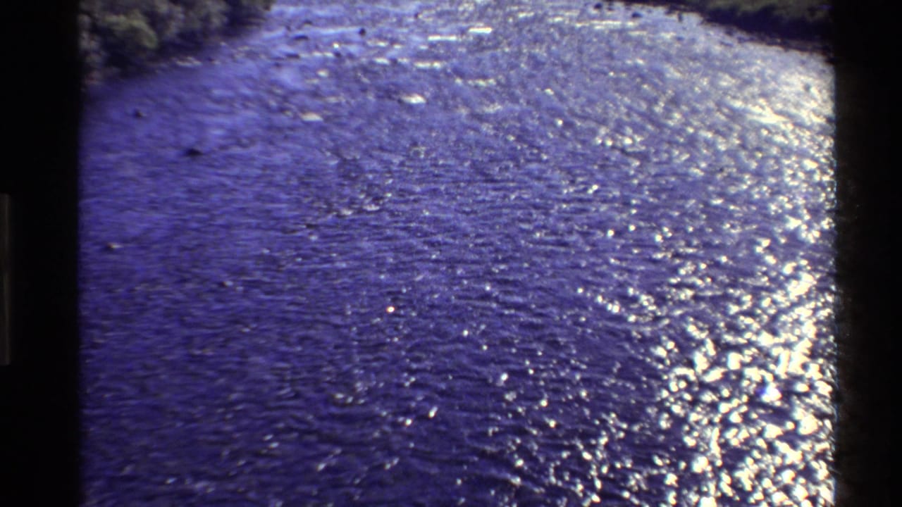 1980 Western U.S. 8mm frame showing a broad river surface shimmering in wind, with low banks and distant hills beyond.