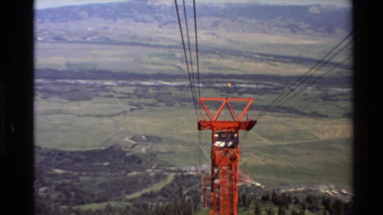 1980 Western USA 8mm frame showing a red tower with suspended wires over a wide mountain valley and distant ridges.