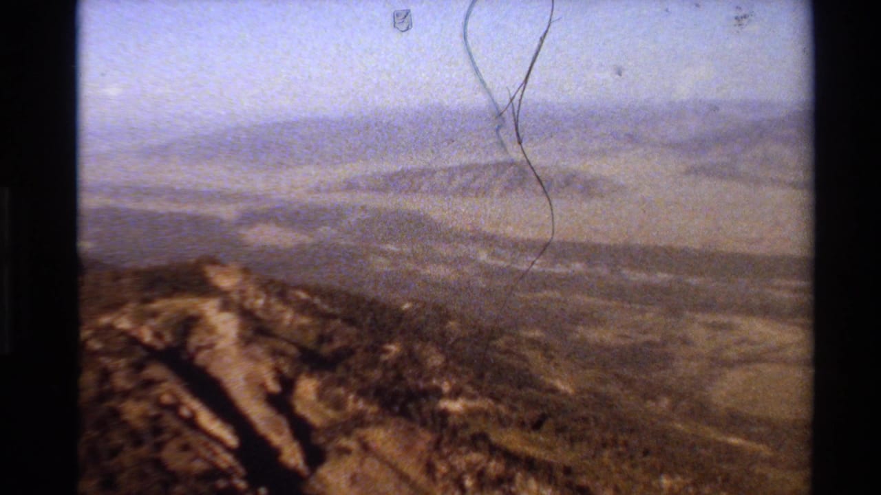 1980 Western USA 8mm frame with a rocky brown ridge below distant hazy mountain layers.