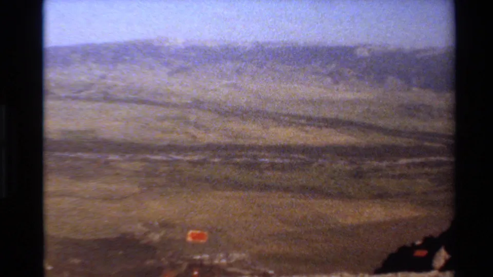 8mm travel footage frame of a hazy Western U.S. mountain panorama with dry terrain and distant ridge lines.