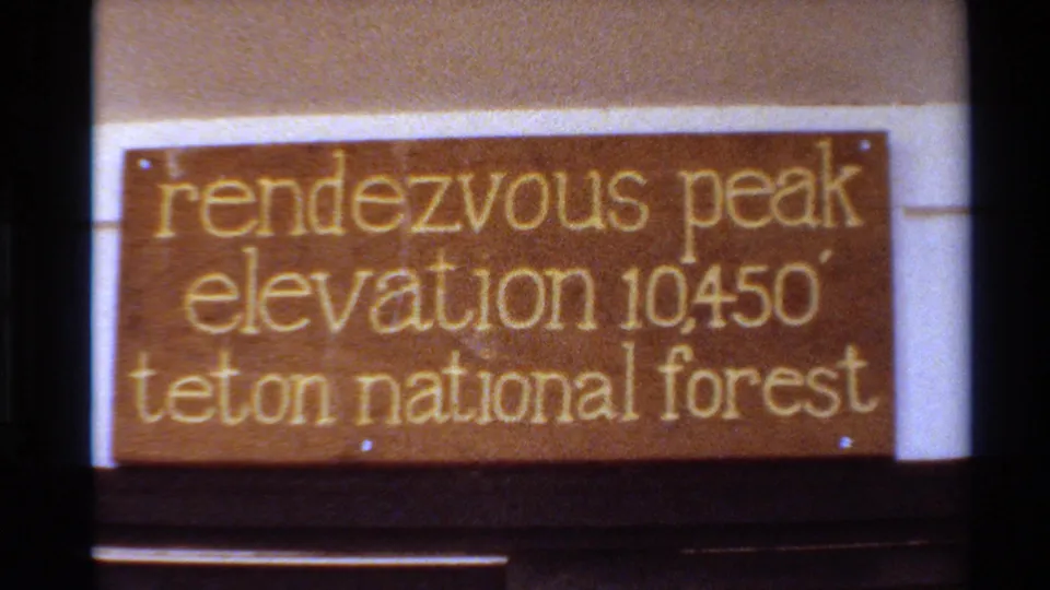 Close 8mm frame of a wooden Rendezvous Peak sign giving elevation 10450 in Teton National Forest.