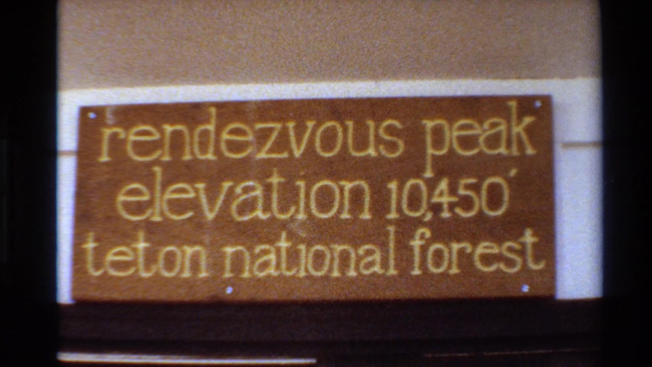 1980 8mm frame showing a close view of a wooden Rendezvous Peak sign reading elevation 10450 feet in Teton National Forest.