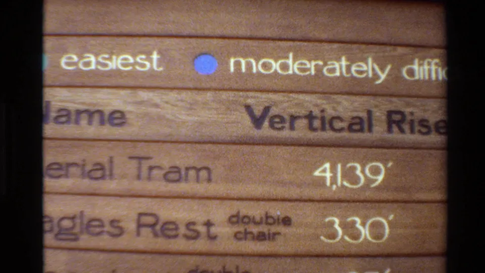 1980 Western USA home-movie frame with a tight view of lift signage listing Aerial Tram at 4,139 feet and Eagles Rest at 330 feet.
