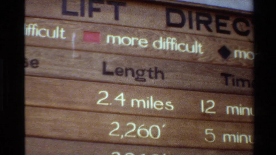 1980 8mm frame of the wooden lift sign, with the length column, partial time column, more difficult text, and black diamond symbol visible.