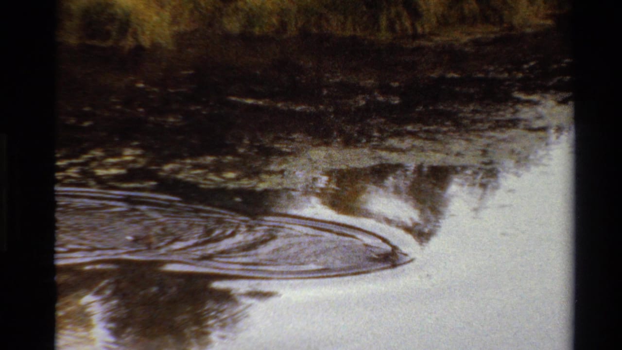 Warm-toned 8mm frame from the Western U.S. showing broad ripples across a calm river or lake surface.
