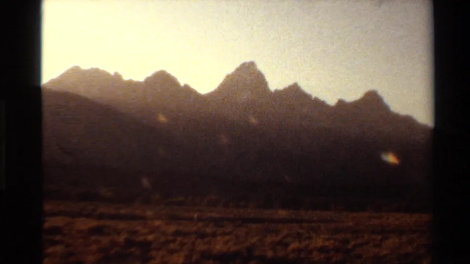 Brief Western U.S. 8mm landscape frame showing a dark mountain ridge silhouetted against a bright, warm sky.