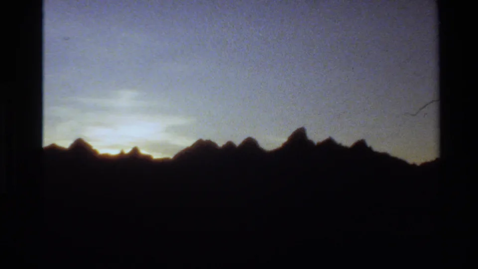 Western USA 1980 8mm frame showing jagged mountain silhouettes against a fading pastel sunset sky.