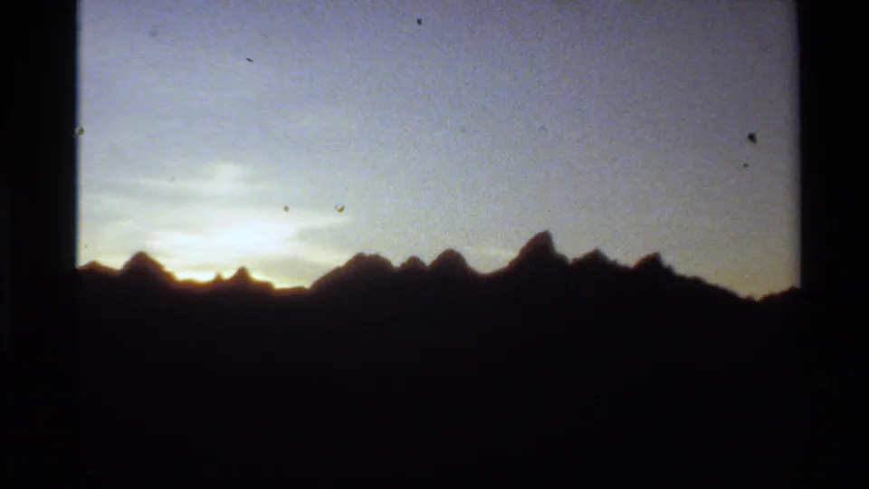 Western USA 1980 8mm frame of silhouetted mountain peaks and soft sunset light along the horizon.