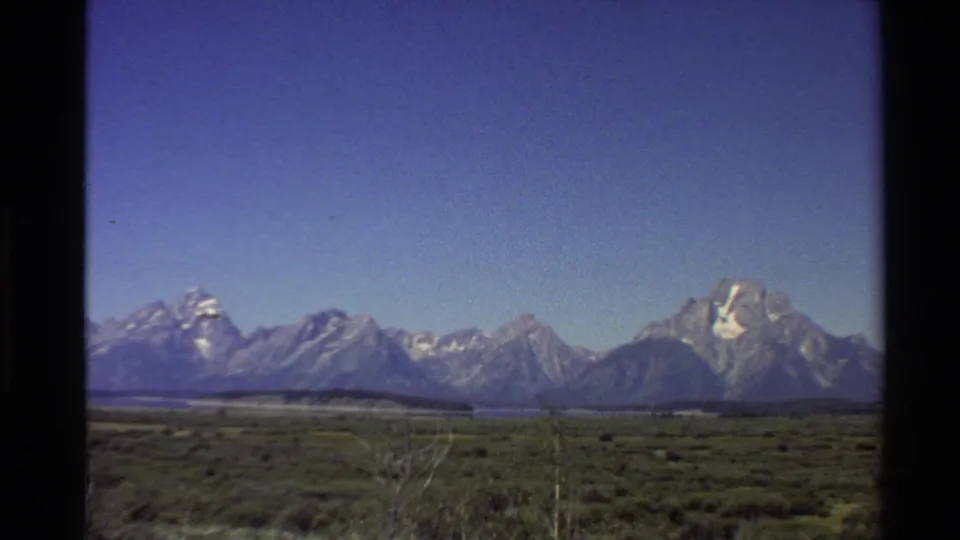 Final 1980 Western USA 8mm frame showing a wide scenic mountain view across open vegetation under clear sky.