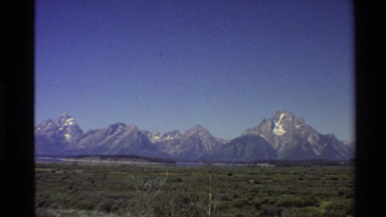 1980 8mm view of the Teton Range rising beyond open sagebrush terrain in the Western United States.