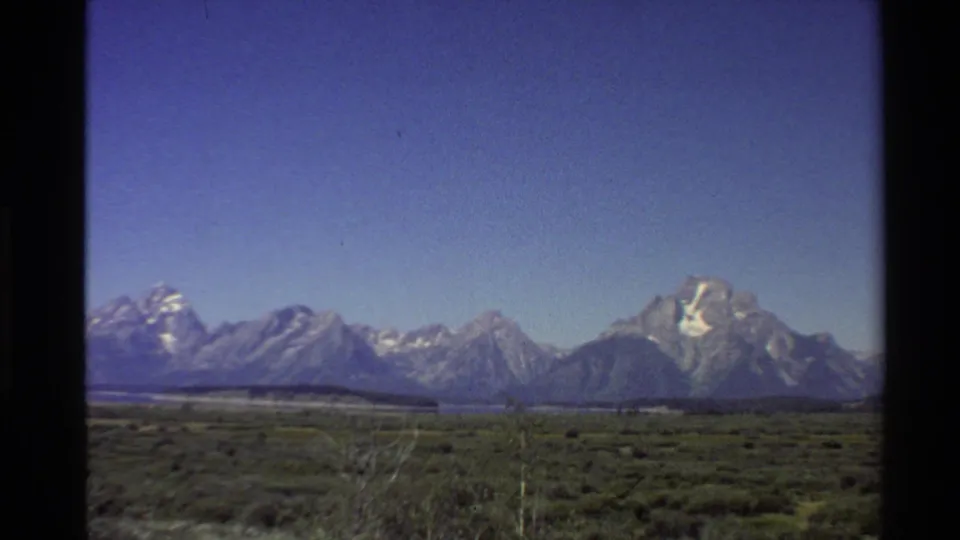 1980 8mm view of the Teton Range rising beyond open sagebrush terrain in the Western United States.