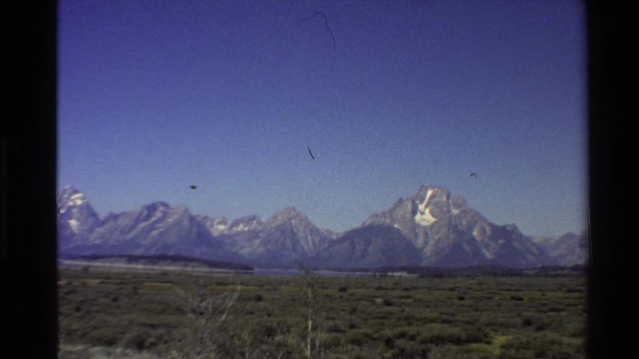 Mountain peaks and a broad valley landscape framed by dark film borders.