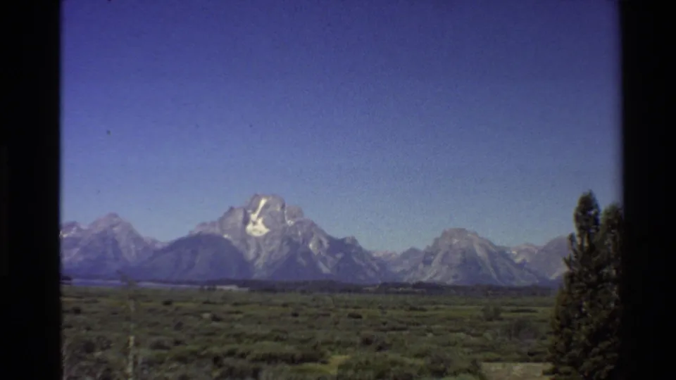 1980 8mm frame of the Teton Range and open valley, with visible film borders and soft color typical of home-movie footage.