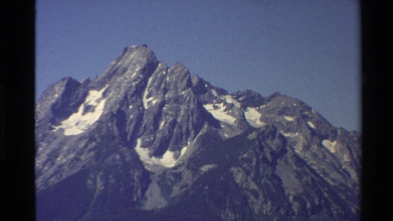 1980 8mm Western United States travel footage showing rugged snow-patched mountain peaks under clear blue sky.