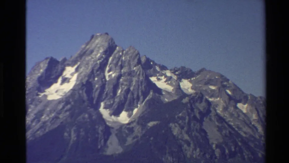 1980 8mm Western United States travel footage showing rugged snow-patched mountain peaks under clear blue sky.