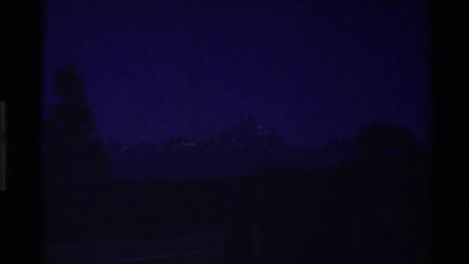 Dark blue 8mm frame that appears to show a dim shoreline or treeline with water or land in the foreground.