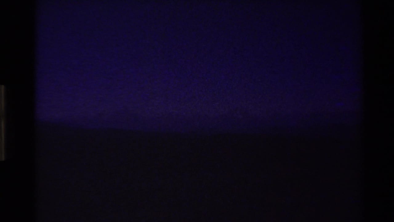 Opening 1980 8mm frame from the Western U.S. appears nearly dark, with only a faint horizon and cool purple-blue sky visible.