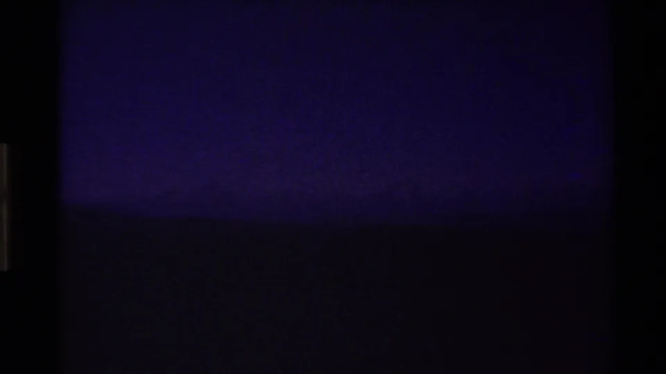 Opening 1980 8mm frame from the Western U.S. appears nearly dark, with only a faint horizon and cool purple-blue sky visible.