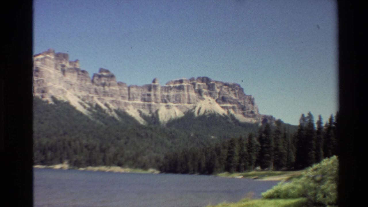 Lake and evergreen shoreline below a pale rocky mountain range.