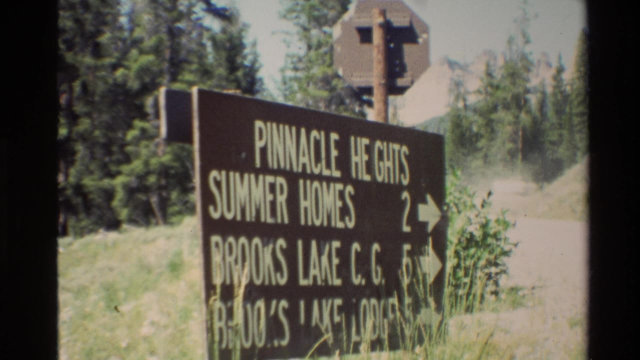 Roadside sign with Pinnacle Heights and Brooks Lake text near trees.