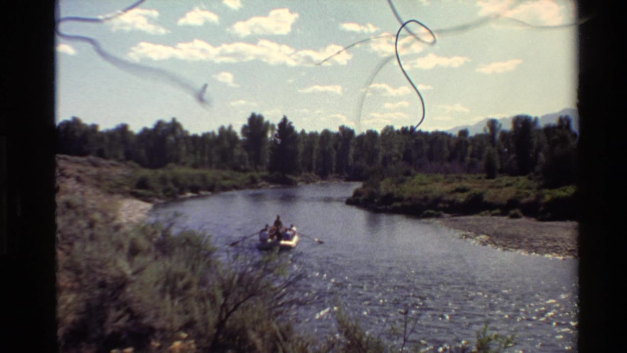 Rowboat with people on a river, seen from shore through 8mm film scratches.