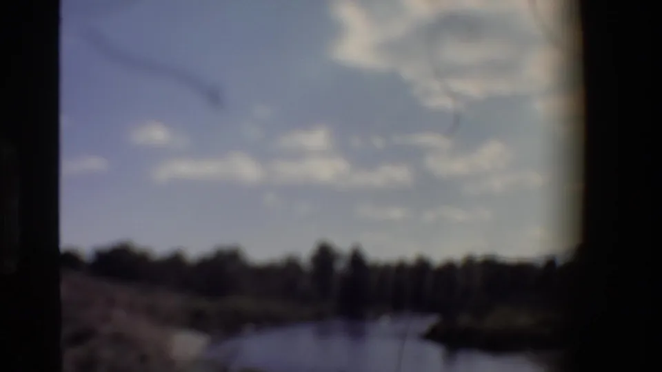 Soft, out-of-focus 1980 Western U.S. 8mm frame showing river, trees, sky, and cloud shapes as the camera loses focus.
