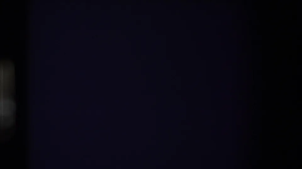 Dark opening frame from an 8mm home movie, with only a faint vertical light shape visible along the left side.