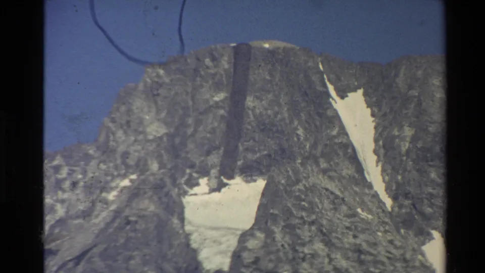 1980 Western U.S. home-movie frame holding on a distant rocky mountain top with snow remnants and visible 8mm frame borders.