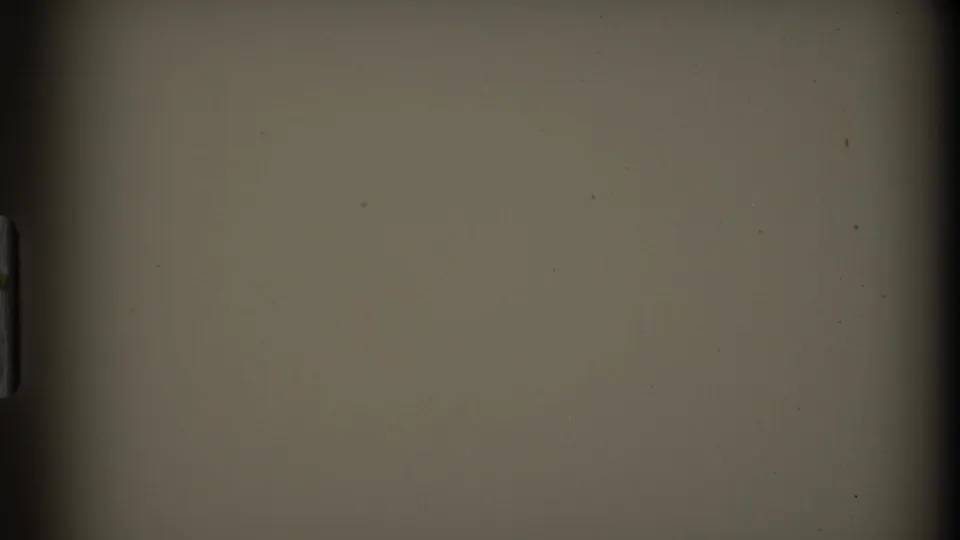 Blank or unexposed 8mm film area following the mountain view, showing beige film tone, gate shadowing, and small surface marks.
