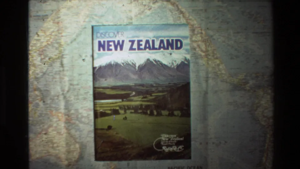 A slightly shifted 8mm frame shows the Discover New Zealand book on the map, with the Pacific Ocean label partly visible below.