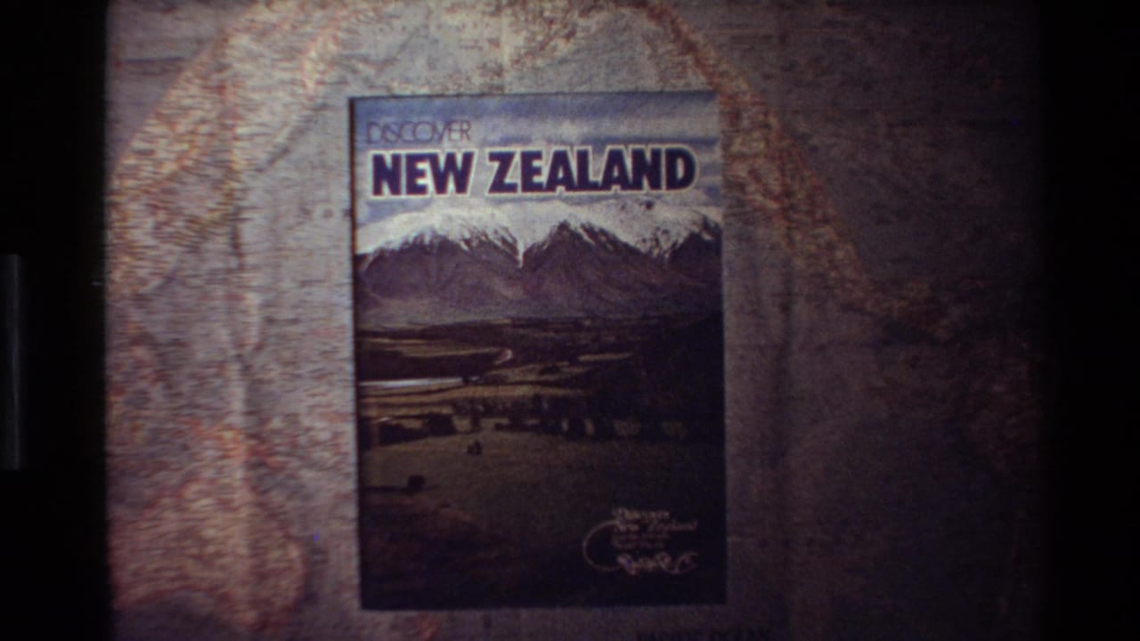 1981 8mm frame showing a Discover New Zealand travel brochure projected against a map-like background.