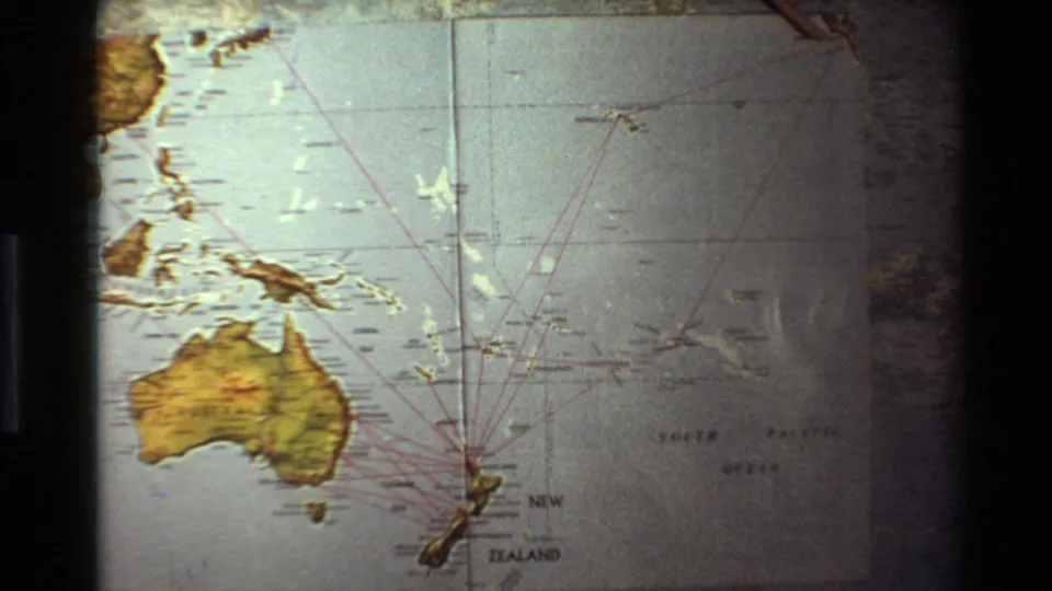 1981 8mm frame of a South Pacific map projection with Australia, New Zealand, nearby islands, and red travel lines.