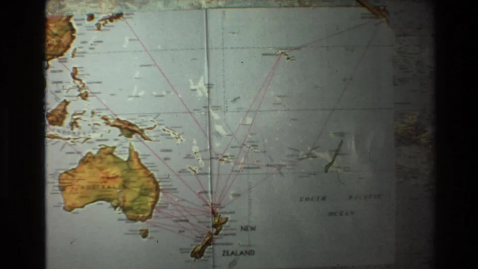 1981 8mm frame of the Australia and New Zealand map as a wooden pointer approaches route lines over the South Pacific.
