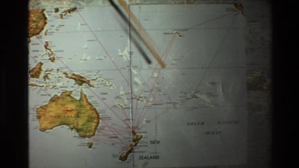 1981 8mm frame with a wooden pointer crossing the map above Australia, New Zealand, and South Pacific flight-route lines.
