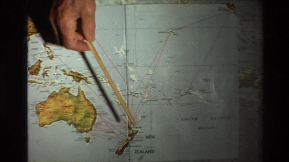 1981 8mm frame showing a hand using a wooden pointer on a Pacific map labeled Australia and New Zealand.