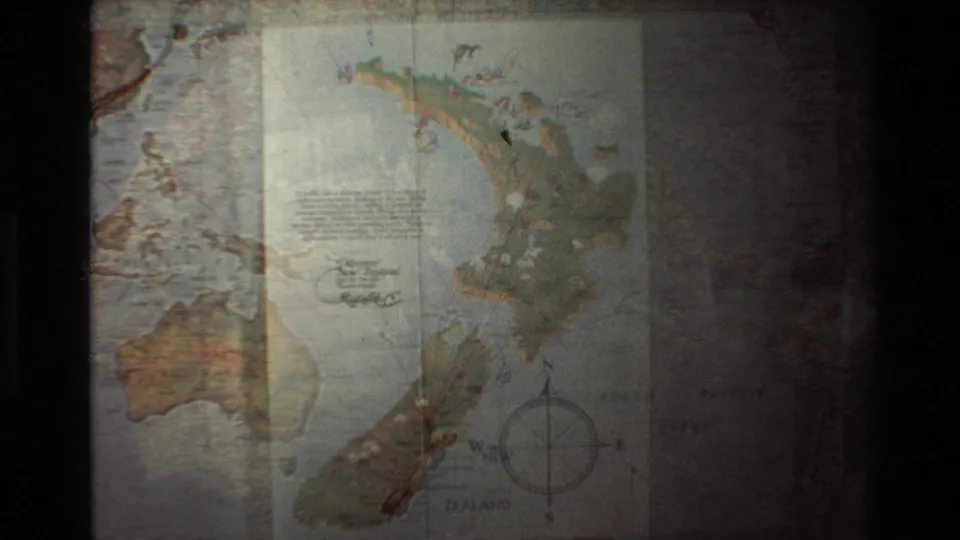 Soft 8mm frame showing an illustrated New Zealand map emerging over the earlier Pacific route map.