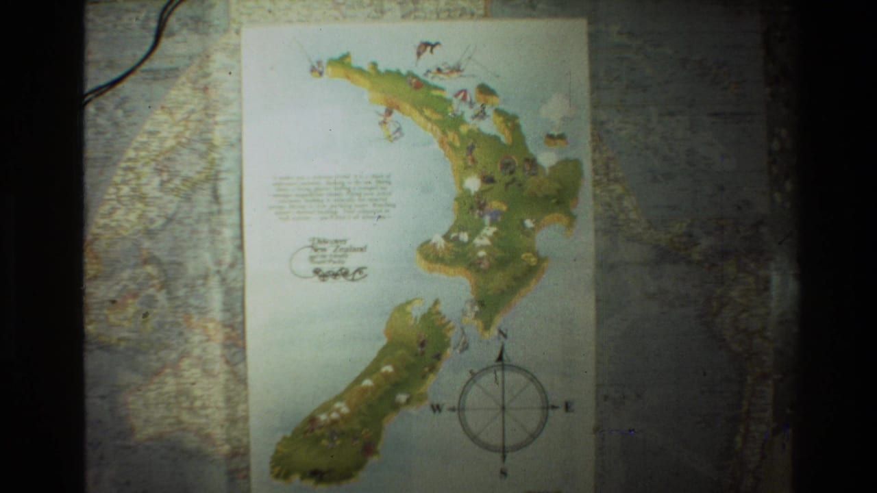 The frame holds on the illustrated New Zealand map, with island shapes, small drawings, and a compass rose visible on 8mm film.