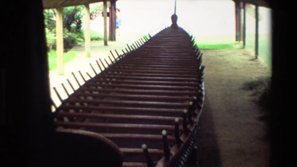 1981 New Zealand frame showing a closer look along the waka's seated interior under the wooden shelter.