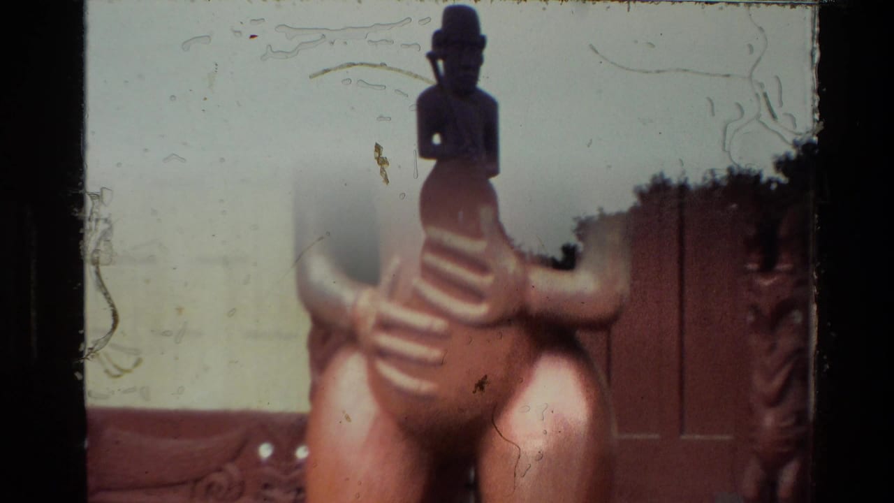 1981 New Zealand 8mm frame showing a carved wooden figure on a building roofline, with cloudy sky and dark film edges.