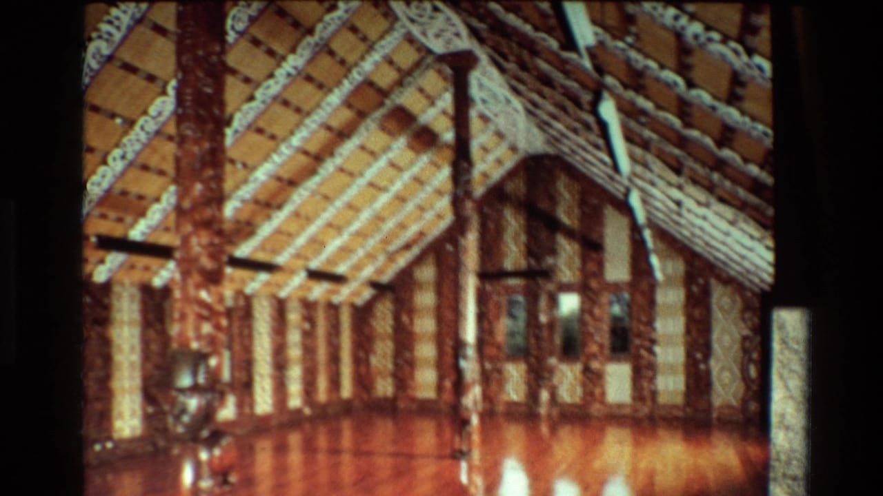 1981 New Zealand 8mm frame showing carved timber posts, decorated rafters, and a polished floor inside a Māori meeting house.