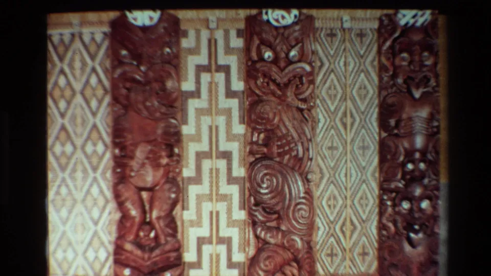 1981 New Zealand 8mm frame with carved Maori woodwork, spiral motifs, and woven geometric panels in a warm interior.