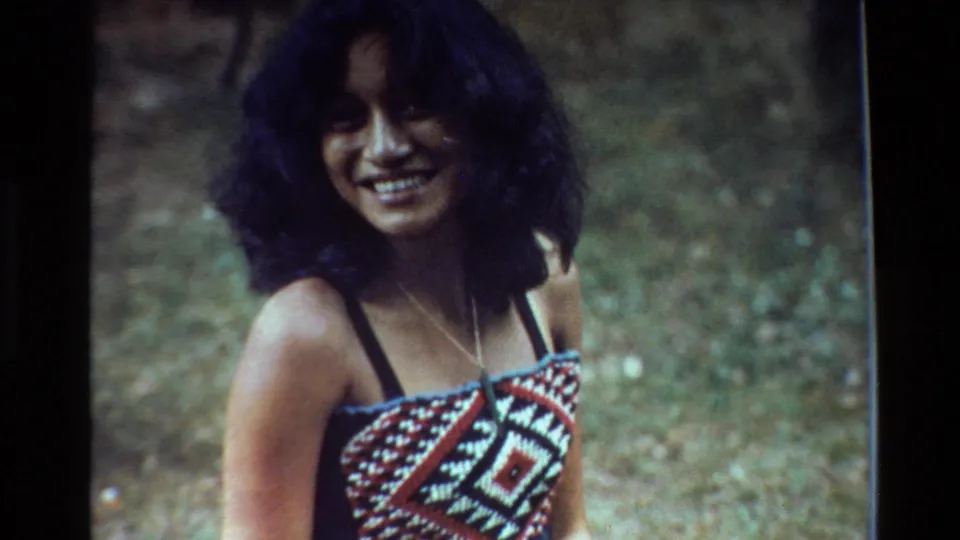 The final frame keeps the woman centered in a soft 8mm outdoor portrait, smiling in a patterned summer top with New Zealand 1981 context from metadata.